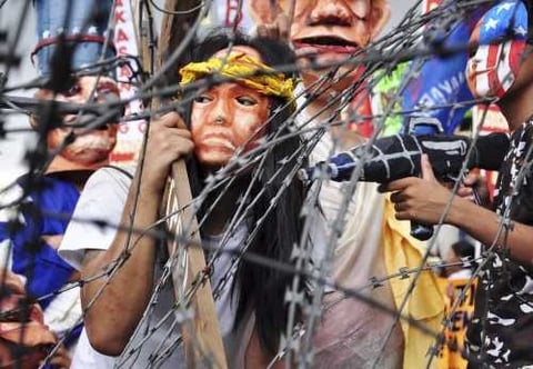 Estudiantes filipinos disfrazados recrean la crucifixión de Cristo mientras marchan hacia el palacio presidencial Malacanang en Manila, Filipina.