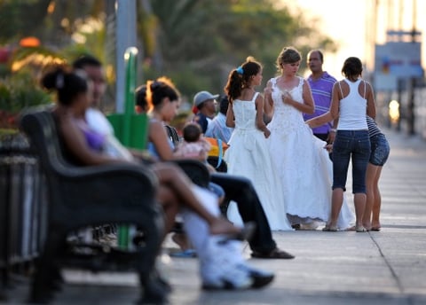 Una joven es ayudada por sus familiares a acomodar su vestido de quinceañera antes de posar para el fotógrafo en la Habana