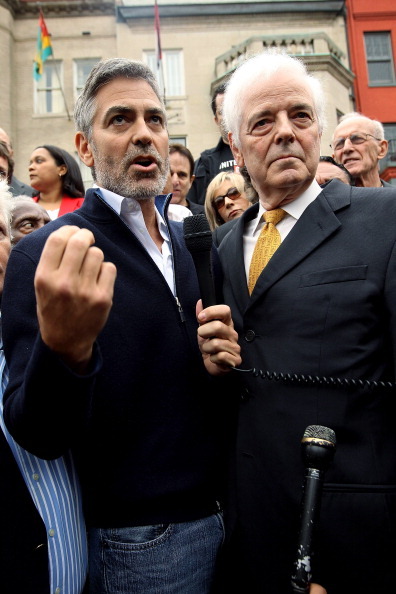 El actor George Clooney (L) habla como su padre, el periodista Nick Clooney (R) escucha durante una protesta frente a la embajada Sudanesa.