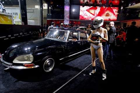 Una modelo posa en bikini y con un casco cubriendo su cabeza al lado de un Citröen DS de época en el Salón del Automóvil de China.