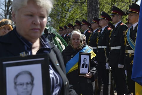 Unas mujeres sostienen fotografías de sus seres queridos durante la ceremonia del 26 aniversario del accidente.