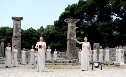 La actriz Ino Menegaki, vestida como una sacerdotisa, estuvo de pie frente al Templo de Hera, de 2,600 años de antigüedad, y después de una invocación a Apolo, el antiguo Dios Sol de los griegos, utilizó un espejo para concentrar los rayos de astro y encender una antorcha.