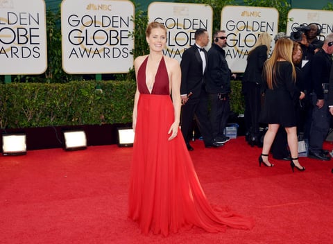 La sensual actriz de American Hustle, Amy Adams, luciendo un vestido en tonos rojizos y con un escote pronunciado.