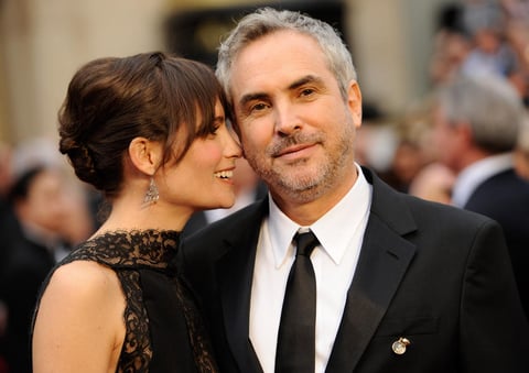 El mexicano Alfonso Cuáron en la Alfombra Roja acompañado por su esposa.