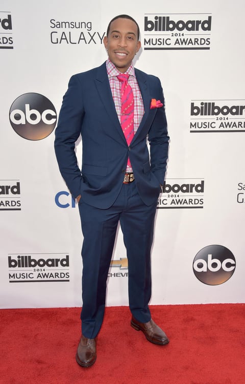Ludacris con un traje azul y corbata y camisa en tonos rosas.