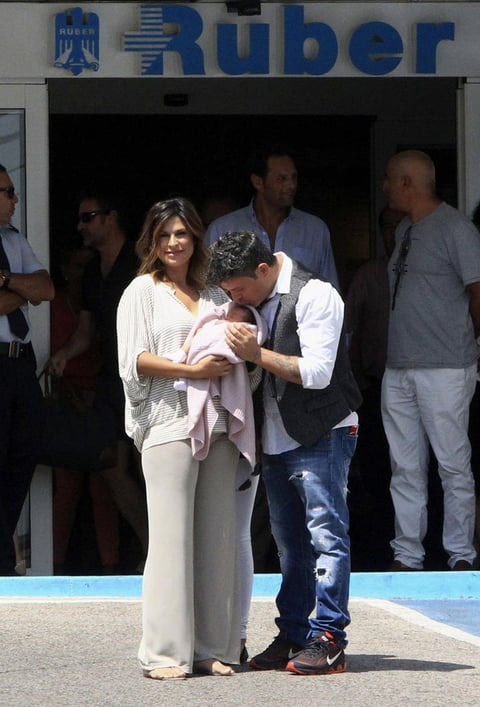 El músico vestido con camisa blanca, con un chaleco gris, una pequeña corbata y pantalón azul salió del centro hospitalario junto a su mujer que vestía un pantalón ajustado de color claro y una blusa a rayas y llevaba a su hija arropada en una arrullo rosa.