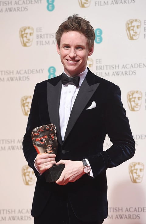 El joven británico Eddie Redmayne sosteniendo entre sus manos el reconocimiento a Mejor Actor por su papel en la película La Teoría del Todo.