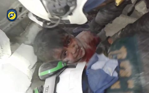 Rescatistas tratando de sacar a un niño atrapado bajo los escombros de un edificio en el barrio de Maadi, Alepo, Siria.