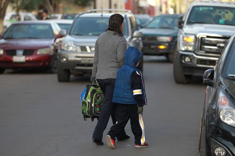 Padres de familia cubrieron a sus hijos para llevarlos a la escuela.