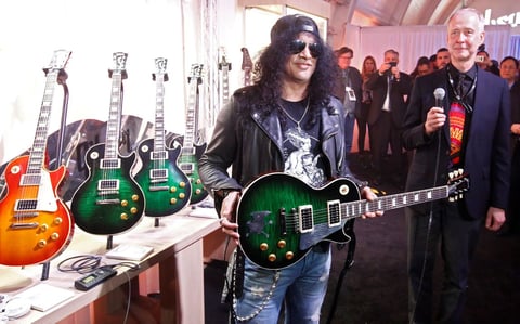 Slash posando con una Robot Les Paul Studio color verde, junto al director ejecutivo de la compañía en una presentación.