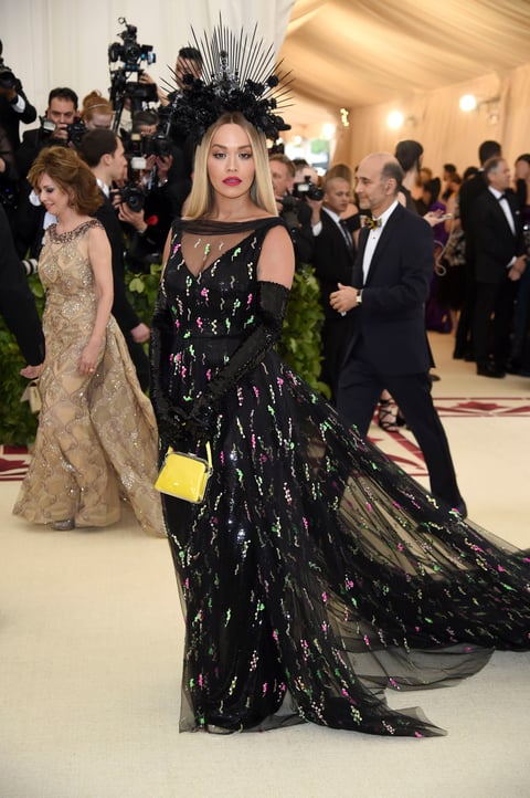 La cantante británica Rita Ora luce un vestido negro con transparencias y detalles rosas y verdes en lentejuelas, a demás de un pequeño bolso amarillo fluorescente.