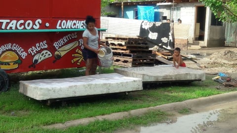 Una ciudadana lava el colchón luego de la inundación que se registró en Piedras Negras.