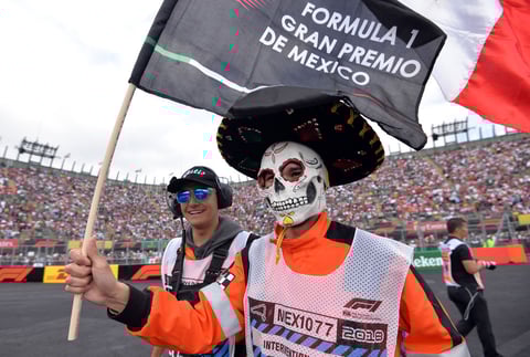 Un asistente maquillado como Catrina agita una bandera durante el Gran Premio de México.,