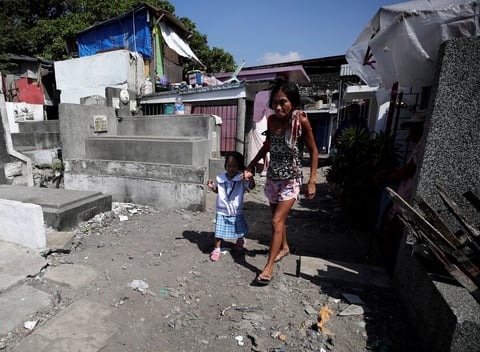 Michaela Sipalay lleva a su hija a la escuela entre las tumbas de un cementerio donde se encuentra su casa.