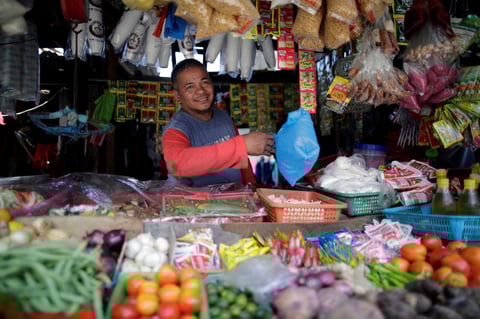 Federico Indicio, de 50 años, despacha a un cliente en su puesto en un mercado.