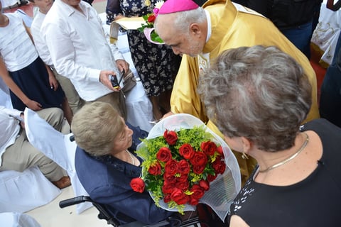 El obispo bajó hasta donde estaba para entregarle un ramo de flores.
