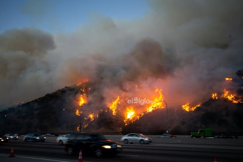 Vehículos transitan frente a un incendio cerca del Centro Getty en Los Angeles, Estados Unidos, el 28 de octubre de 2019. Miles de residentes fueron obligados a evacuar sus hogares después de que los incendios forestales de rápido crecimiento estallaran el lunes por la mañana cerca del famoso Centro Getty, en el oeste del estado estadounidense de California.