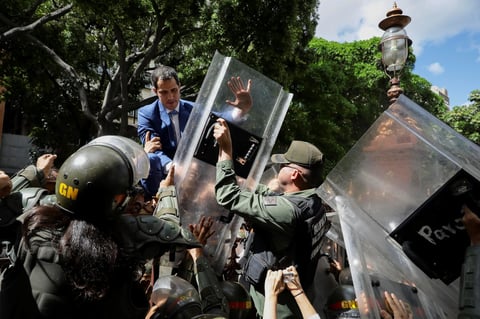 El líder opositor venezolano Juan Guaidó trepa una reja en un intento por ingresar a la sede de la Asamblea Nacional, custodiada por la policía para impedir su ingreso y el de diputados opositores este domingo, en Caracas (Venezuela). Guaidó denunció que el país vivió este domingo 'el asesinato de la República' al elegir el chavismo a un nuevo presidente de la Asamblea Nacional (AN, Parlamento) en una sesión a la que le impidieron entrar, así como a un grupo de diputados opositores. La trifulca comenzó cuando intentó acceder a la sede de la AN y fue repelido por los miembros de la GNB. Intentó entonces subir por una verja que da acceso al hemiciclo pero los agentes lo impidieron con los escudos