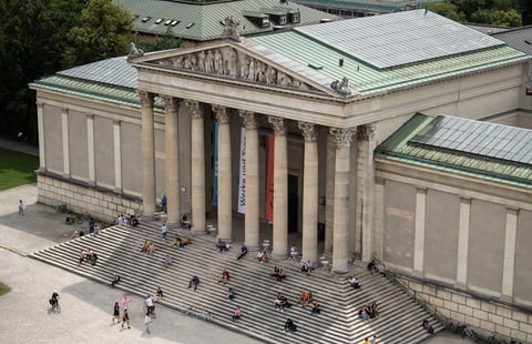 La gente disfruta del sol en las escaleras del palacio de la Colección de Antigüedades en la Koenigsplatz 