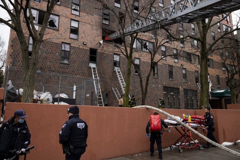 Firefighters and NYPD officers work outside an apartment building after a fire in the Bronx, Sunday, Jan. 9, 2022, in New York. (AP Photo/Yuki Iwamura)