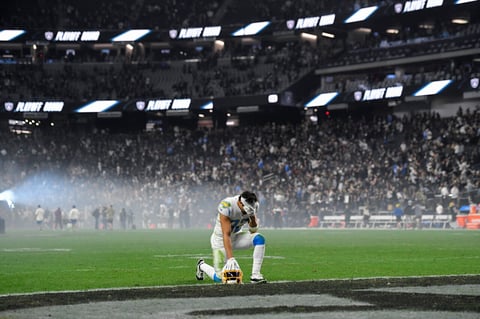 Los Angeles Chargers safety Alohi Gilman (32) kneels with his head in his hands after the Los Angeles Chargers lost to the Las Vegas Raiders in overtime of an NFL football game, Sunday, Jan. 9, 2022, in Las Vegas. (AP Photo/David Becker)