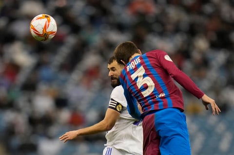 Real Madrid's Karim Benzema heads the ball in front of Barcelona's Gerard Pique during the Spanish Super Cup semi final soccer match between Barcelona and Real Madrid at King Fahd stadium in Riyadh, Saudi Arabia, Thursday, Jan. 13, 2022. (AP Photo/Hassan Ammar)
