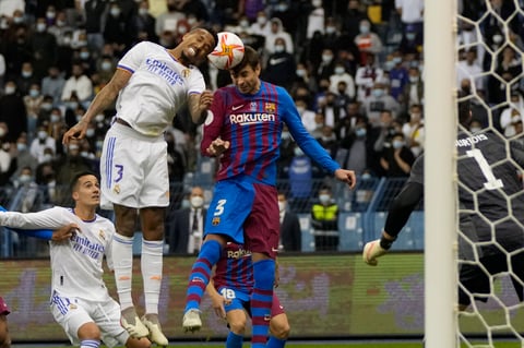 Real Madrid's Eder Militao, left, and Barcelona's Gerard Pique jump for the ball during the Spanish Super Cup semi final soccer match between Barcelona and Real Madrid at King Fahd stadium in Riyadh, Saudi Arabia, Thursday, Jan. 13, 2022. (AP Photo/Hassan Ammar)