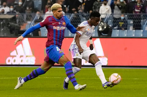 Real Madrid's Vinicius Junior in action to score by Barcelona's Ronald Araujo during the Spanish Super Cup semi final soccer match between Barcelona and Real Madrid at King Fahd stadium in Riyadh, Saudi Arabia, Wednesday, Jan. 12, 2022. (AP Photo/Hassan Ammar)