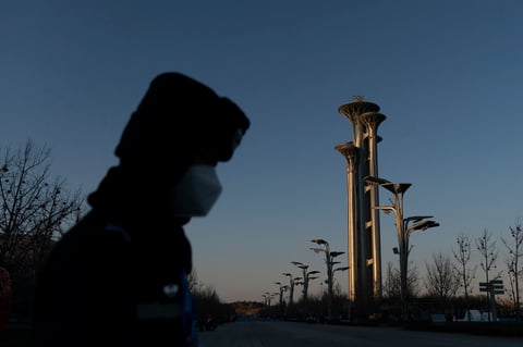A police officer stands next to a barricade as the Beijing Olympic Tower is lit by the setting sun at the 2022 Winter Olympics, Tuesday, Jan. 25, 2022, in Beijing. (AP Photo/Jae C. Hong)