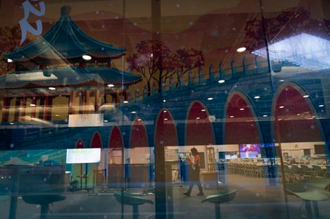 An Olympic worker is seen through a window film depicting the Seventeen Arch Bridge of the Summer Palace at the 2022 Winter Olympics, Tuesday, Jan. 25, 2022, in Beijing. (AP Photo/Jae C. Hong)
