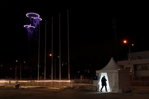 A man walks through an access control point outside the main media center as the Beijing Olympic Tower stands lit in the background at the 2022 Winter Olympics, Tuesday, Jan. 25, 2022, in Beijing. (AP Photo/Jae C. Hong)