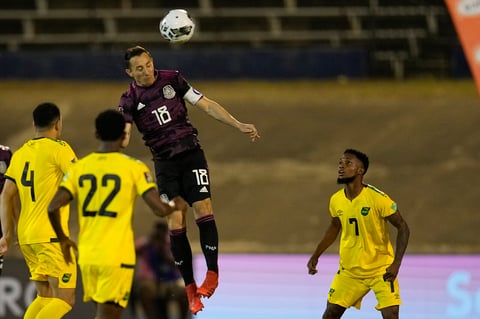 Mexico's Jose Andres Guardado heads the ball under the watch of Jamaica's Lamar Walker, right, during a qualifying soccer match for the FIFA World Cup Qatar 2022 in Kingston, Jamaica, Thursday, Jan. 27, 2022. (AP Photo/Ramon Espinosa)