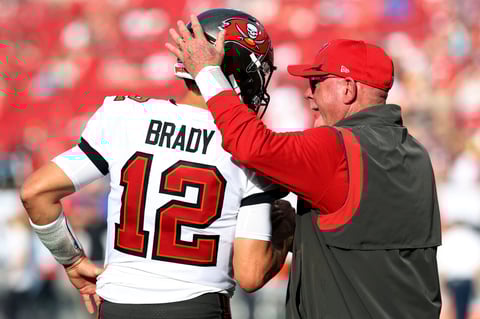 Tampa Bay Buccaneers head coach Bruce Arians talks to quarterback Tom Brady (12) before an NFL football game against the Carolina Panthers Sunday, Jan. 9, 2022, in Tampa, Fla. (AP Photo/Mark LoMoglio)