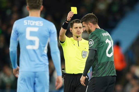 Sporting's Paulinho, right, is shown a yellow card during the Champions League round of 16 second leg soccer match between Manchester City and Sporting Lisbon at the City of Manchester Stadium in Manchester, England, Wednesday, March 9, 2022. (AP Photo/Dave Thompson)