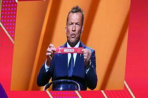 Former German soccer international and manager Lothar Matthaus is projected on a giant screen as he holds up the name of Mexico during the 2022 soccer World Cup draw at the Doha Exhibition and Convention Center in Doha, Qatar, Friday, April 1, 2022. (AP Photo/Hussein Sayed)