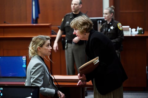 US actress Amber Heard speaks with her lawyer Elaine Bredehoft during the $50 million Depp vs Heard deformation trail at the Fairfax County Circuit Court April 12, 2022, in Fairfax, Virginia. - 'Pirates of the Caribbean' star Johnny Depp physically and sexually abused his then-wife Amber Heard during drug- and alcohol-fueled binges in which he became a 'monster,' her lawyers told a court on Tuesday. (Photo by Brendan SMIALOWSKI / POOL / AFP)