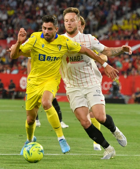SEVILLA, 29/04/2022.- El centrocampista del Cádiz Rubén Sobrino (i) trata de escapar de Ivan Rakitic, del Sevilla, durante el partido de Liga en Primera División que disputan este viernes en el estadio Ramón Sánchez-Pizjúan. EFE/Raúl Caro