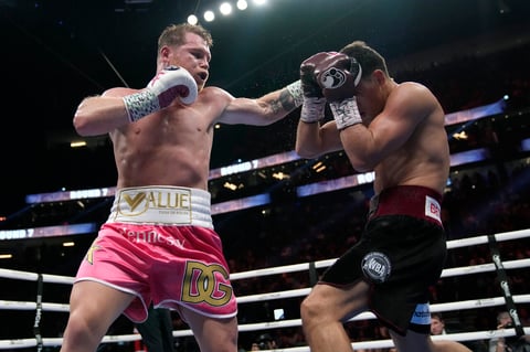 Canelo Alvarez, left, of Mexico, throws a punch against Dmitry Bivol, of Kyrgyzstan, during a light heavyweight title fight, Saturday, May 7, 2022, in Las Vegas. (AP Photo/John Locher)