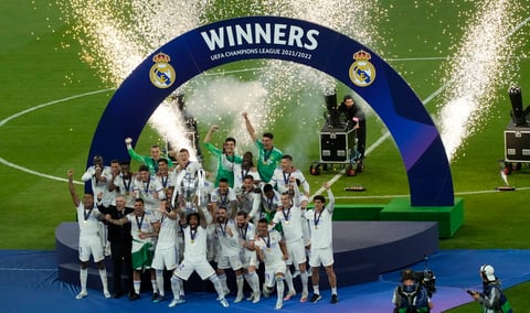 Real Madrid players hold the trophy and celebrate after winning the Champions League final soccer match between Liverpool and Real Madrid at the Stade de France in Saint Denis near Paris, Saturday, May 28, 2022. (AP Photo/Christophe Ena)