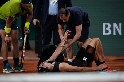Germany's Alexander Zverev holds his right ankle after twisting it, as Spain's Rafael Nadal, left, looks on during their semifinal match at the French Open tennis tournament in Roland Garros stadium in Paris, France, Friday, June 3, 2022. (AP Photo/Christophe Ena)