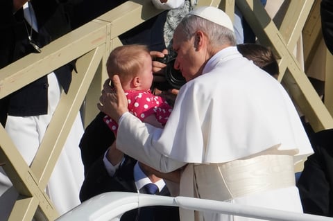 Pope Leo XIV caresses a baby on his popemobile as he tours St. Peter's Square at the Vatican prior to the inaugural Mass of his pontificate, Sunday, May 18, 2025. (AP Photo/Domenico Stinellis)