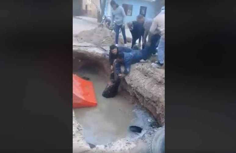 Al final se aprecia que un vecino lleva una escalera con la cual se ayudan para poder sacarlo de la zanja. (ESPECIAL)