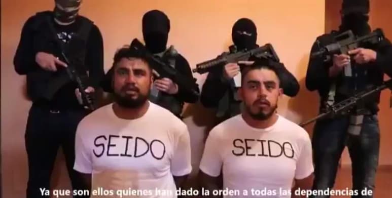 Un escalofriante video mostró el lunes a dos agentes de inteligencia de México atados y arrodillados, confesando supuestas violaciones de derechos humanos y rodeados por cinco hombres enmascarados y armados que les apuntan con pistolas y fusiles. (ESPECIAL)