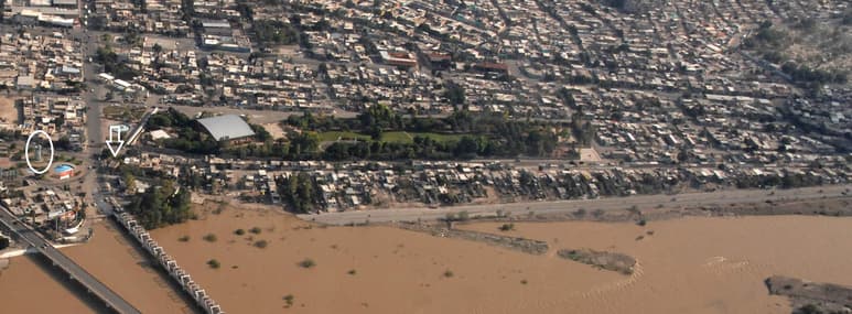 En esta foto de Ramón Sotomayor Jr., tomada durante la avenida del Nazas en 2008, se aprecia en el óvalo el monumento erigido en 1974; la flecha señala el edificio con las compuertas del Canal del Coyote. Transversalmente, se observan los vestigios de la presa del Coyote. Y en el extremo derecho, se distingue también el comienzo del cerro, en cuyas faldas fue construido el primer torreón por don Pedro Santa Cruz.