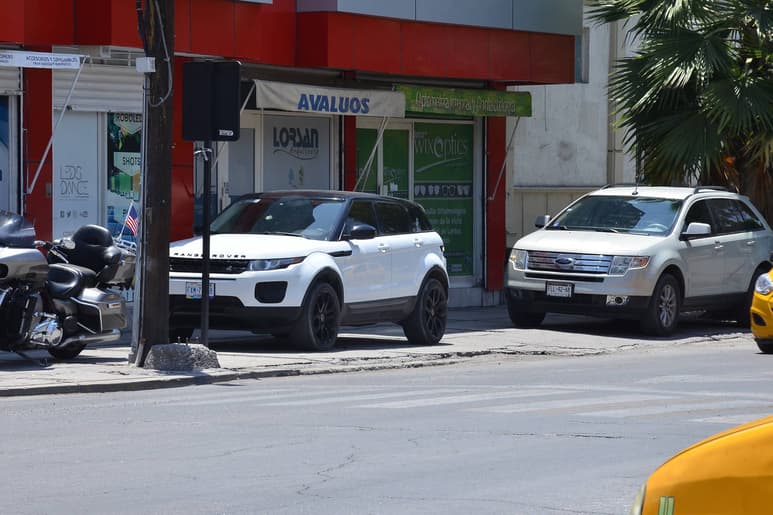 Confusión. Agentes de Tránsito quitan las placas de los vehículos que se estacionan sobre las banquetas en la calzada Colón. Algunos obstruyen el paso peatonal y otros no. (FERNANDO COMPEÁN)