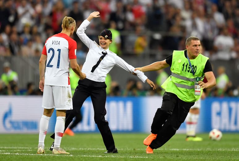Un guardia de seguridad saca a una mujer de la cancha tras haber ingresado en la final de la Copa del Mundo entre Croacia y Francia.
