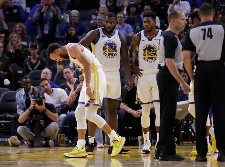 Stephen Curry hace un gesto de dolor después de que Aron Baynes, de Soles, le cayera encima en la segunda mitad del juego del miércoles. (AP)