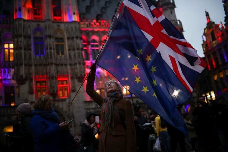 Una mujer belga sostiene las banderas de la Unión Europea y el Reino Unido un día antes de la salida del reinado del bloque. (AP)