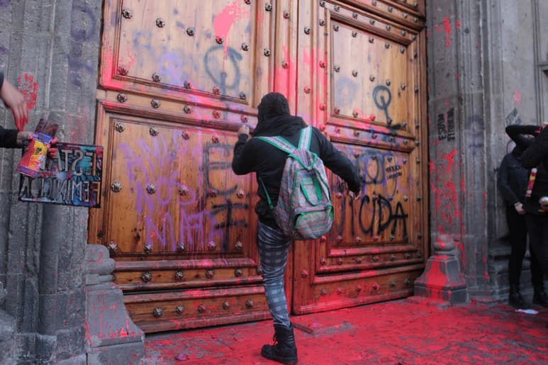 La mañana de este viernes, un grupo de personas encapuchadas se manifestó afuera de Palacio Nacional y realizó varias pintas en la fachada del recinto ubicado en el Centro Histórico de la Ciudad de México. (NOTIMEX)