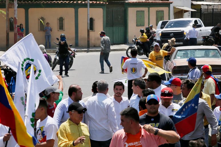 Un hombre apunta un arma (i) a una multitud a favor de Juan Guaidó en Venezuela. (AP)